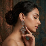 Indian model touching face while wearing oxidized silver double hoop chandbali earrings, vintage background portrait