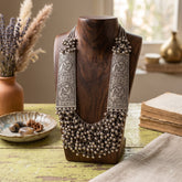 Oxidised engraved plate bib necklace displayed on a wooden stand