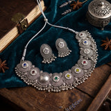 Multicolour medallion choker necklace and matching earrings arranged on teal fabric