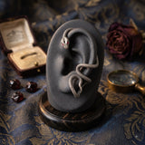 Second view of oxidized silver snake ear cuff with red eye on bronze ear mannequin, slightly different angle showing full serpent coil wrap from helix to lobe with tail curl and red eye detail