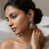 Indian model in neutral grey drape wearing oxidized silver sunflower jhumka earrings, soft lifestyle portrait, hand near ear