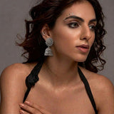 Indian model wearing oxidized silver sunflower jhumka earrings with dark curly hair, grey studio background, editorial look