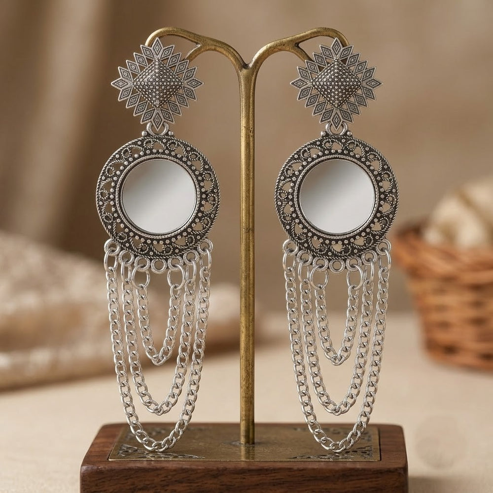 Oxidized silver mirror chandelier earrings displayed upright on brass earring stand, warm studio background
