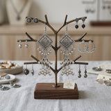Oxidized silver diamond square chandelier jhumka earrings displayed on bronze tree jewellery stand, lifestyle studio setting