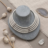Silver-tone multi-layer choker necklace displayed on a stand