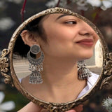 Close-up of oxidized silver sunburst chandbali jhumka earring showing engraving detail and ghungroo drops