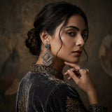 Woman in ethnic outfit holding up oxidized silver diamond jhumka earring to ear