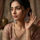Woman wearing oxidized silver diamond jhumka earrings with grey velvet embroidered suit