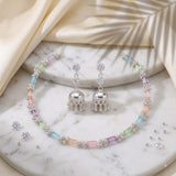 Pastel multicolour necklace and jhumka earrings set styled on a carved background