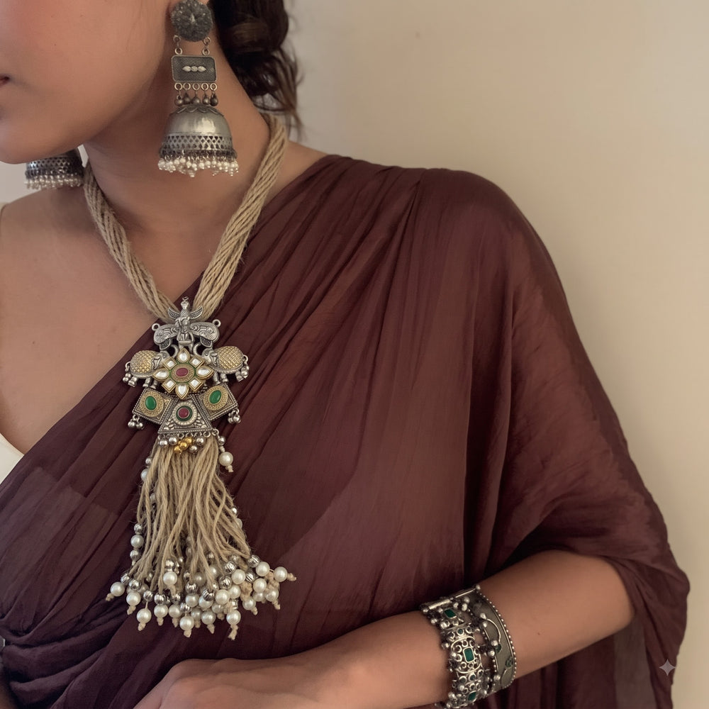 Close-up of a model wearing the layered statement necklace with elephant pendant and tassel