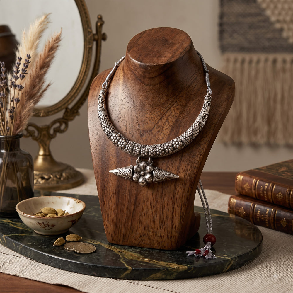 Silver-tone floral necklace arranged on a wooden display stand
