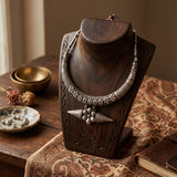 Silver-tone statement necklace displayed on a wooden jewellery stand