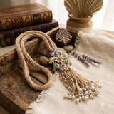 Long elephant pendant and tassel necklace arranged on a neutral aesthetic background