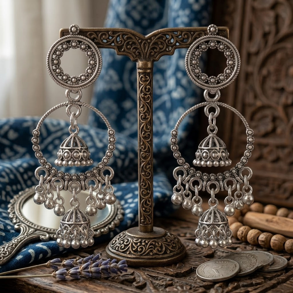 Oxidized silver double hoop chandbali with jhumka earrings on aesthetic stone surface with dried flowers and spices