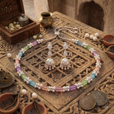 Pastel stone necklace and silver-tone jhumka earrings on marble