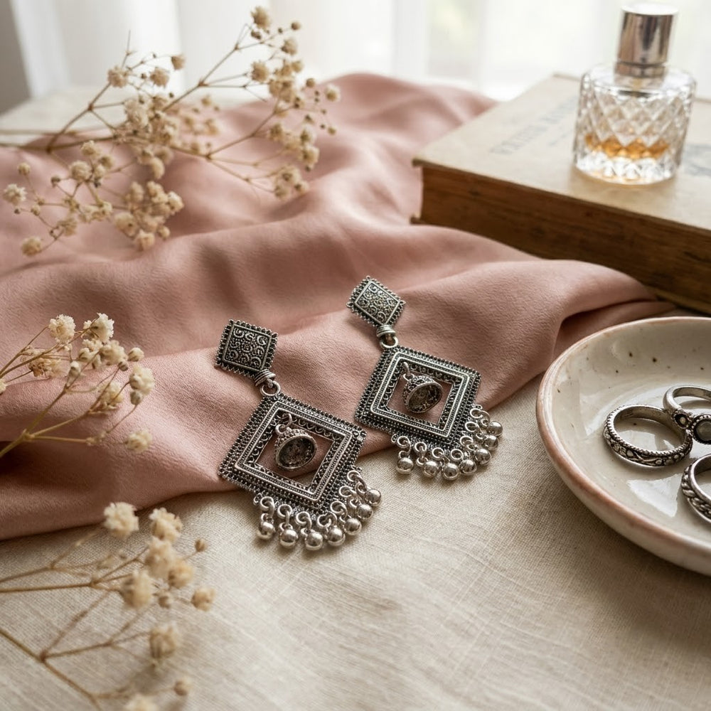 Close-up side profile of woman wearing oxidized silver diamond jhumka earrings