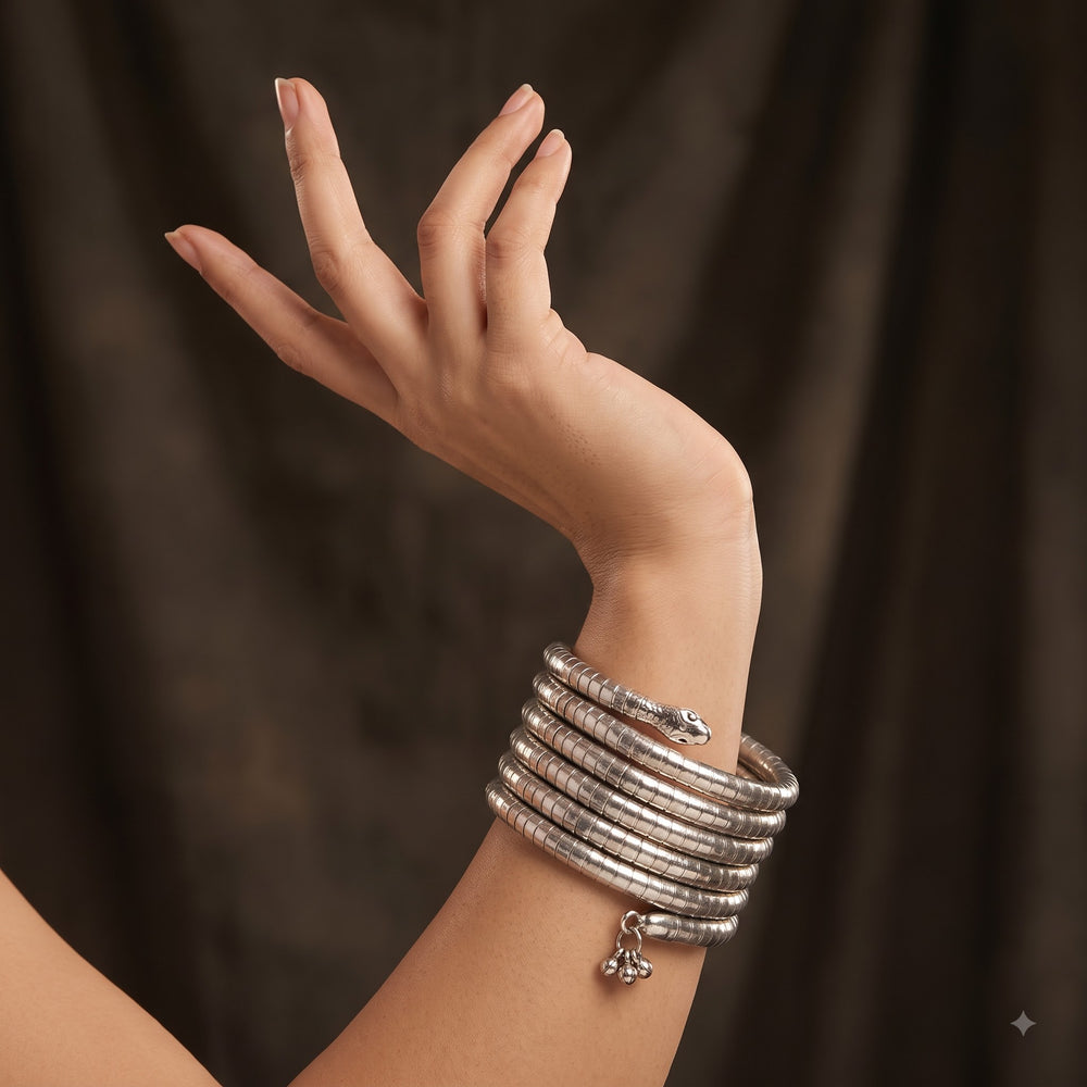 Indian model in black mirror-work blouse with yellow saree wearing silver oxidized snake coil bracelet, close-up of wrist showing all 5 coils and ghungroo charm drops