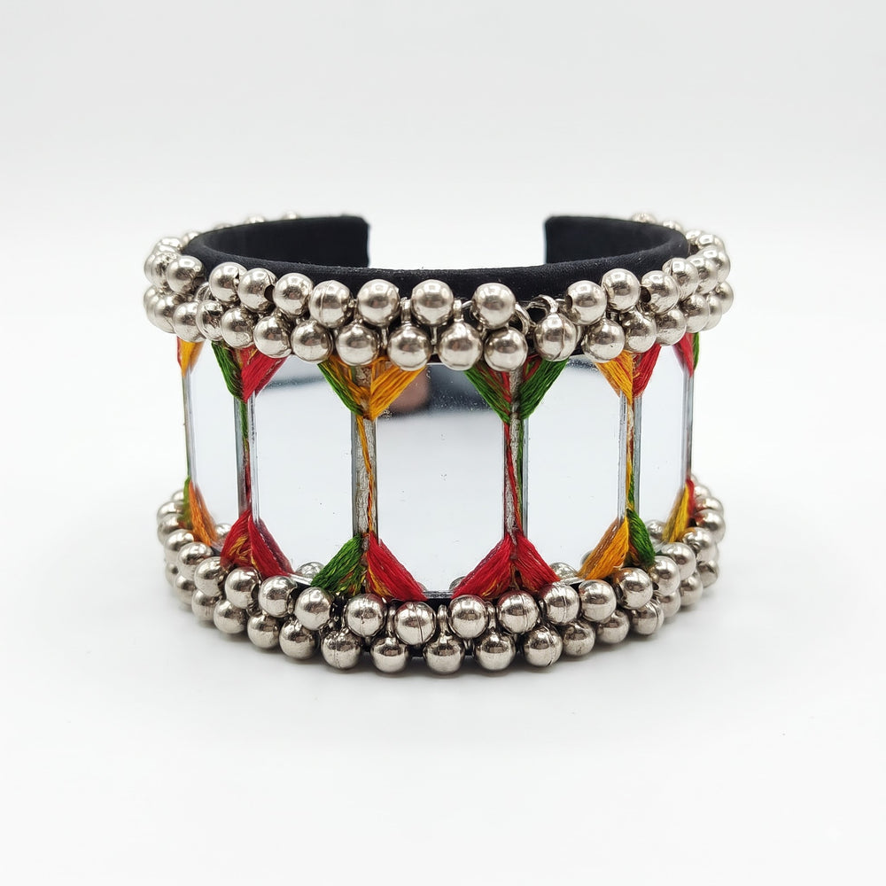 Large mirror tile ghungroo cuff bracelet on white studio background showing full rectangular mirror panels, multicolour red green yellow orange thread zigzag and double silver ghungroo ball borders, front view