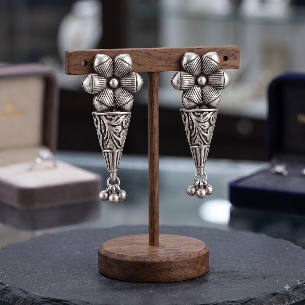 Oxidised floral drop earrings with bead charms on a wooden stand