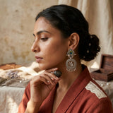 Model wearing oxidized silver Radha-Krishna chandbali earrings, editorial close-up, rust red dupatta