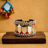 Indian model in yellow chaniya choli with cowrie choker necklace and jhumka earrings wearing large mirror tile ghungroo cuff bracelet, seated on stone steps in full Navratri festive look