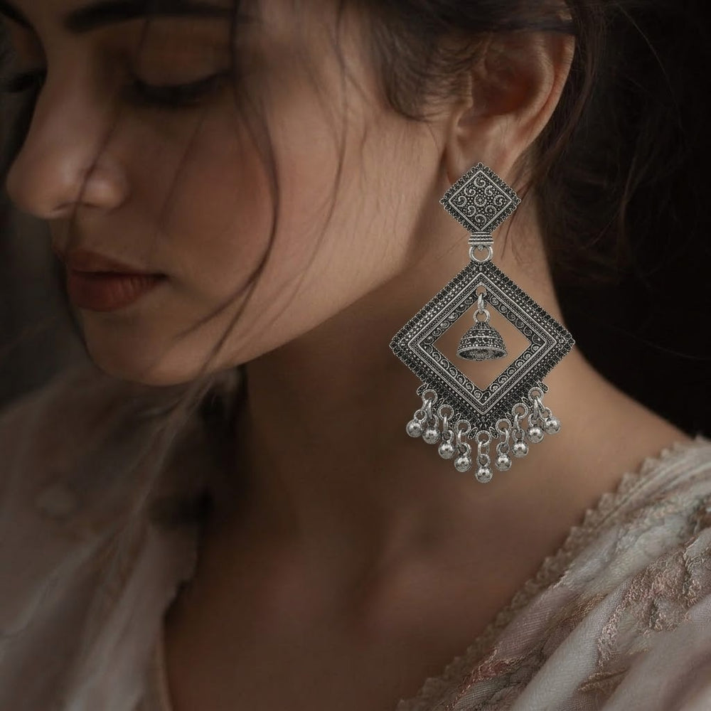 Woman wearing oxidized silver diamond jhumka earrings with dusty rose embroidered saree