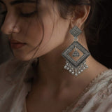 Woman wearing oxidized silver diamond jhumka earrings with dusty rose embroidered saree