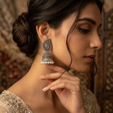 Woman in elegant bun hairstyle wearing oxidized silver paisley jhumka earrings with bridal outfit