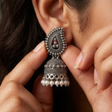 Close-up of woman wearing oxidized silver paisley jhumka earring, hand adjusting earring
