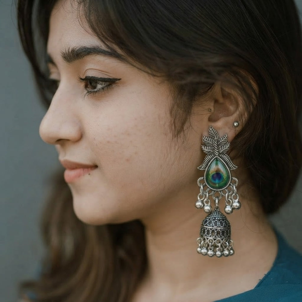 Woman wearing oxidized silver peacock jhumka earrings at festive Navratri setting